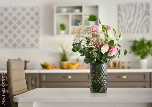Vase with beautiful flowers on table in kitchen