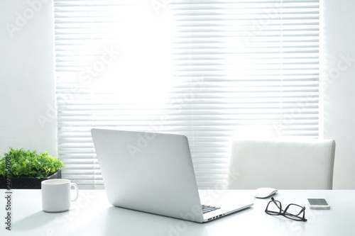 Office workplace with laptop and eye glasses on white table