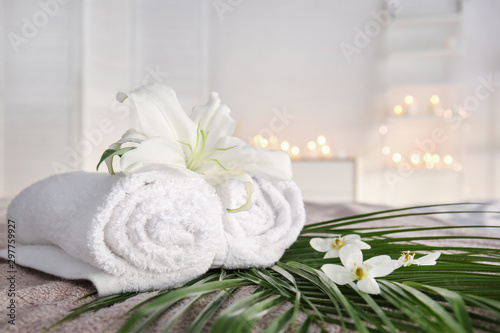 Fototapeta Naklejka Na Ścianę i Meble -  Rolled towels with fresh flowers and tropical leaves in spa salon