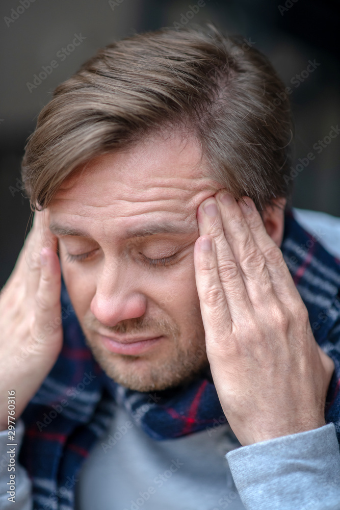 Dark-haired man touching head while having high fever Dark-haired man touching head while having high fever