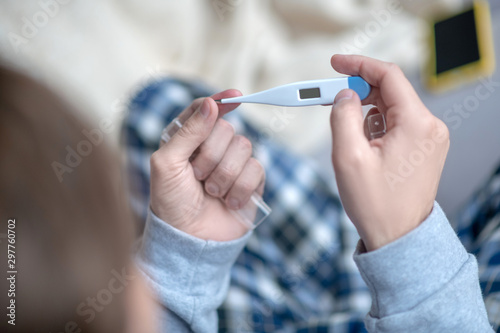 Top view of man taking thermometer while feeling hot