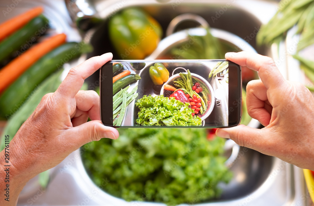 A lady's hands take a picture with her cell phone to clean vegetables. Healthy food to stay in shape and for vegan and vegetarian people