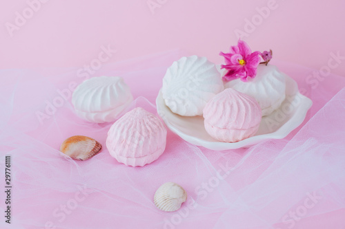 Delicious sweet marshmallows and cute little toy on pastel pink background
