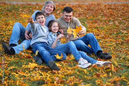 Happy family having holiday in autumn city park. Children and parents posing  smiling  playing and having fun. Bright yellow trees and leaves