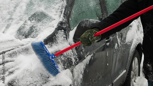 Cleaning the side of the car from the snow using the brush.