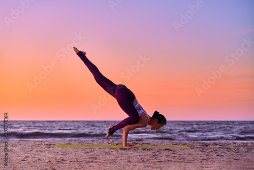 Asian woman doing yoga by the sea at sunset