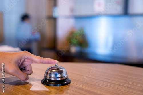 Hand ringing service bell on the cashier table in the countryside hotel