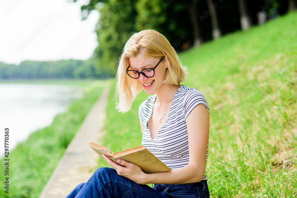 Girl relaxing at riverside after working day. Woman dreaming about vacation. Literature for summer vacation. Rest relax and hobby. Summer vacation. Girl sit on green grass near river and read book Girl relaxing at riverside after working day. Woman dreaming about vacation. Literature for summer vacation. Rest relax and hobby. Summer vacation. Girl sit on green grass near river and read book