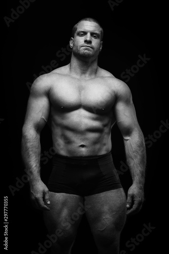 sports man standing on a black background, doing sports.