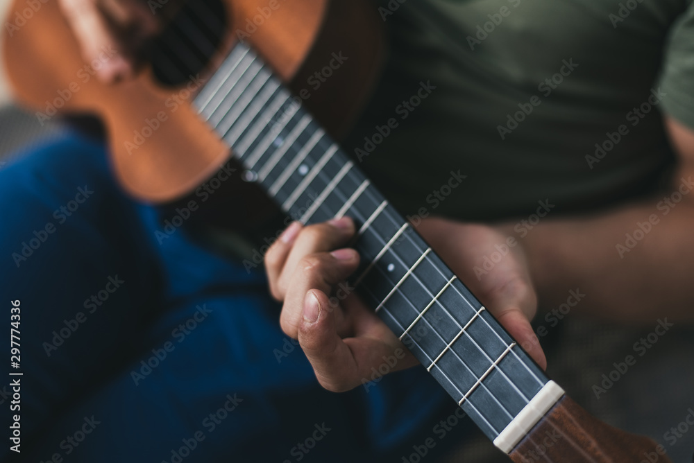 ukulele game. a man playing a little guitar. the performer writes the music on the ukulele at home