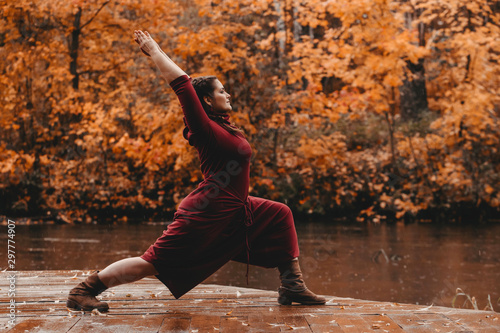 Beautiful curvy girl doing yoga in nature on a autumn day. Body positive, sports for women, harmony, asana, healthy lifestyle, inspiring look, self-love and wellness.