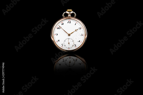 Front view of old antique mechanical golden steel pocket watch isolated on black background.