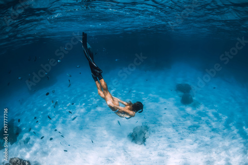 Young woman free diver in bikini glides over sandy sea with fishes. Freediving at Hawaii. © artifirsov