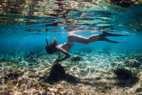 Slim young woman snorkeling over bottom with fish in underwater