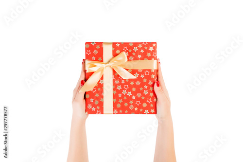 Woman hands give wrapped Christmas or other holiday handmade present in red paper with Gold ribbon. Isolated on white background, top view. thanksgiving Gift box concept © sosiukin