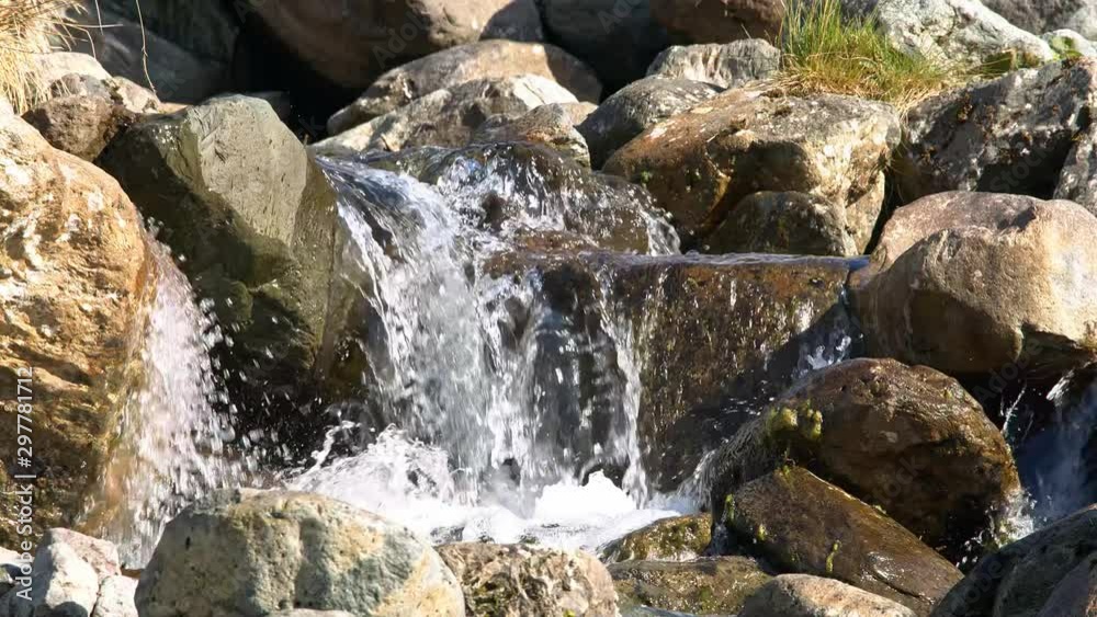Cascading water fall over rocks in lake land mountain scene. Slow motion