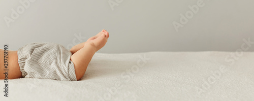 Portrait of a cute 3 months baby lying down on a blanket, beautiful babys legs on bad