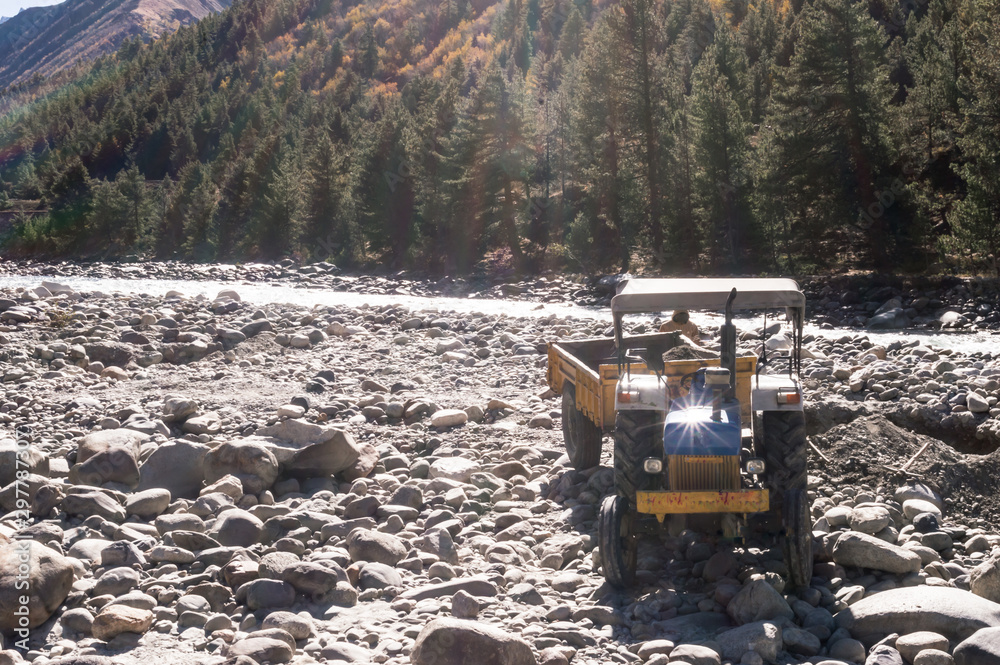 Obraz premium Autonomous dumper Truck Construction vehicle parked on industrial site on bank of Beas River in Manali India with mountain background to construct the concrete walls for reinforcement the river bed.