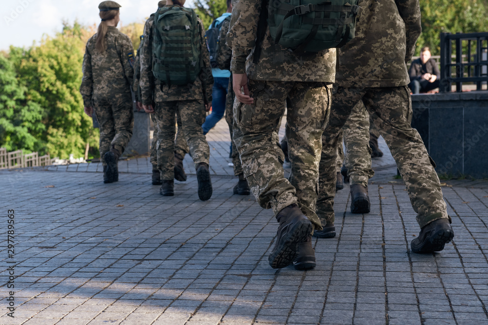 A group of soldiers are walking along the street. People in military uniform in the city. Closeup. A group of soldiers are walking along the street. People in military uniform in the city. Closeup.