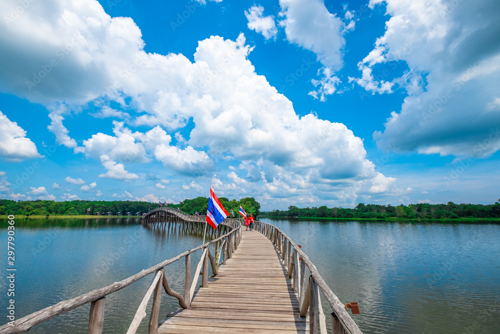 Couple Asian women walking on wood bridge cross the river and blusky with cloud  in Chumphon province.