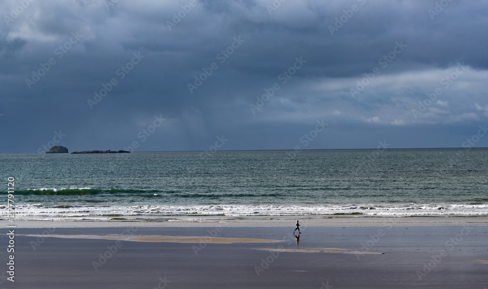 Stormy skies and weather on the wst coast of Ireland,Lone walker in the distance walking on Banna beach Stormy skies and weather on the wst coast of Ireland,Lone walker in the distance walking on Banna beach