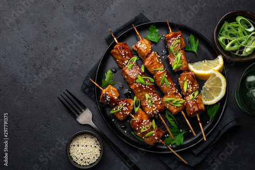 Teriyaki salmon skewers on black plate photo