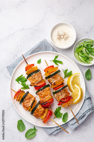 Grilled salmon and vegetables skewers on white plate