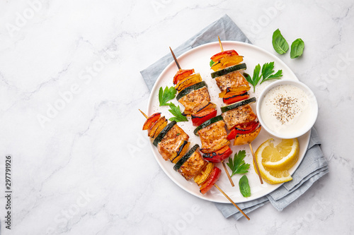 Grilled salmon and vegetables skewers on white plate