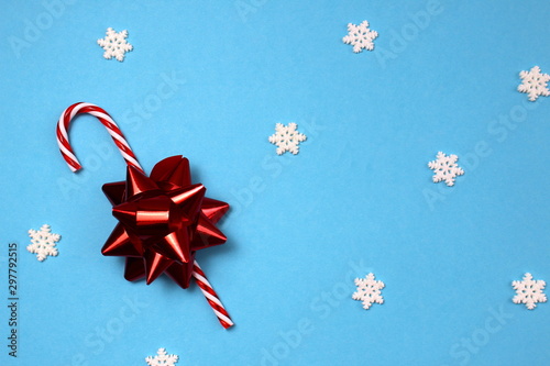 on a blue background lies a candy cane with a bow
