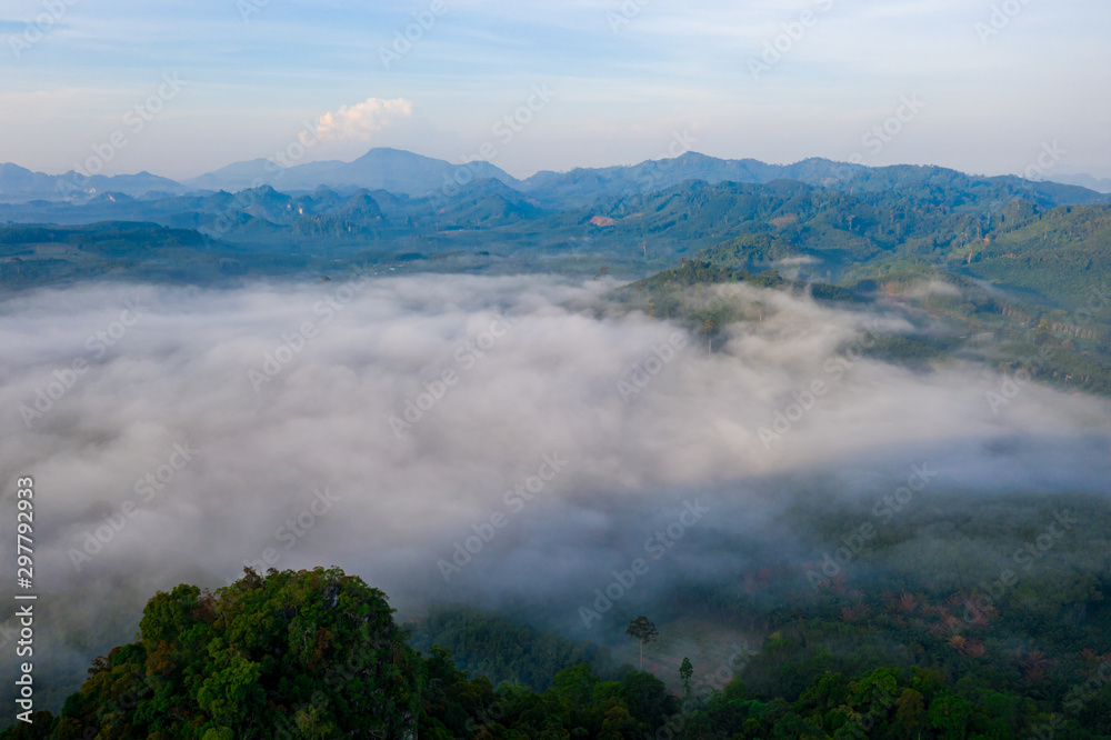 Obraz premium Aerial view of mountains with cloud cover mountain at sunrise and blue sky in Surat Thani Province, Thailand.