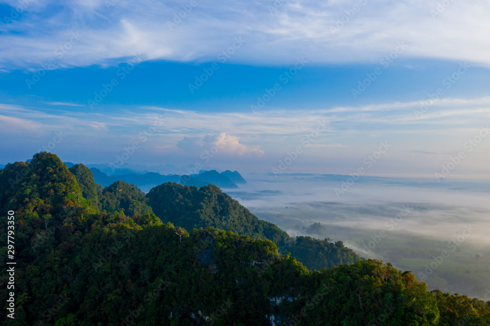 Aerial view of mountains with cloud cover mountain at sunrise and blue sky in Surat Thani Province, Thailand.