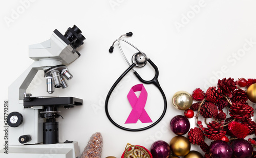 Christmas decoration with a microscope, a stethoscope and a pink bow, as support and support for people affected by cancer