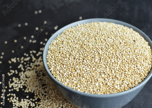 Pile of quinoa grain seeds in bowl over dark stone table background