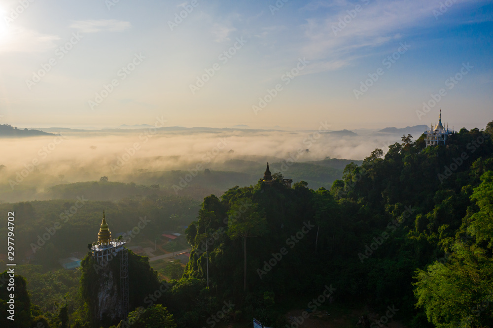 Aerial view of mountains with cloud cover mountain at sunrise, blue sky, pagoda on the mountain in Surat Thani Province, Thailand.