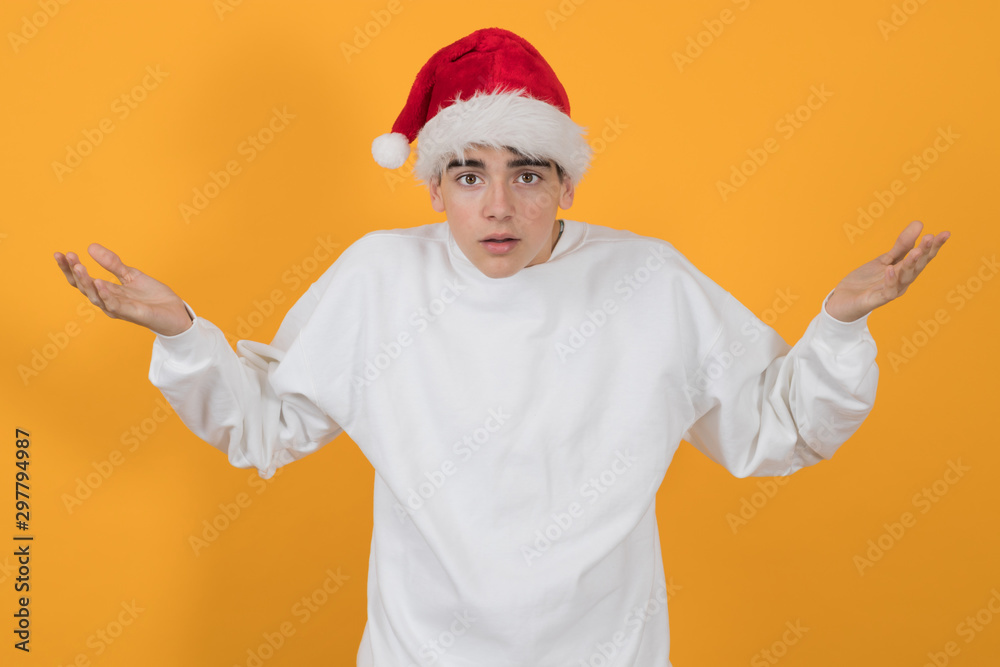 young teenage man with santa claus hat isolated on color background young teenage man with santa claus hat isolated on color background