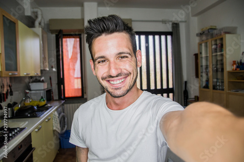 Photo of handsome man taking a selfie at home smiling on the camera photo