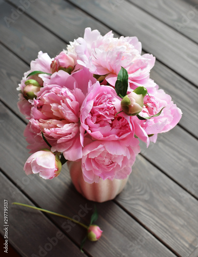 Bouquet of pink peony flowers in vase on wooden background
