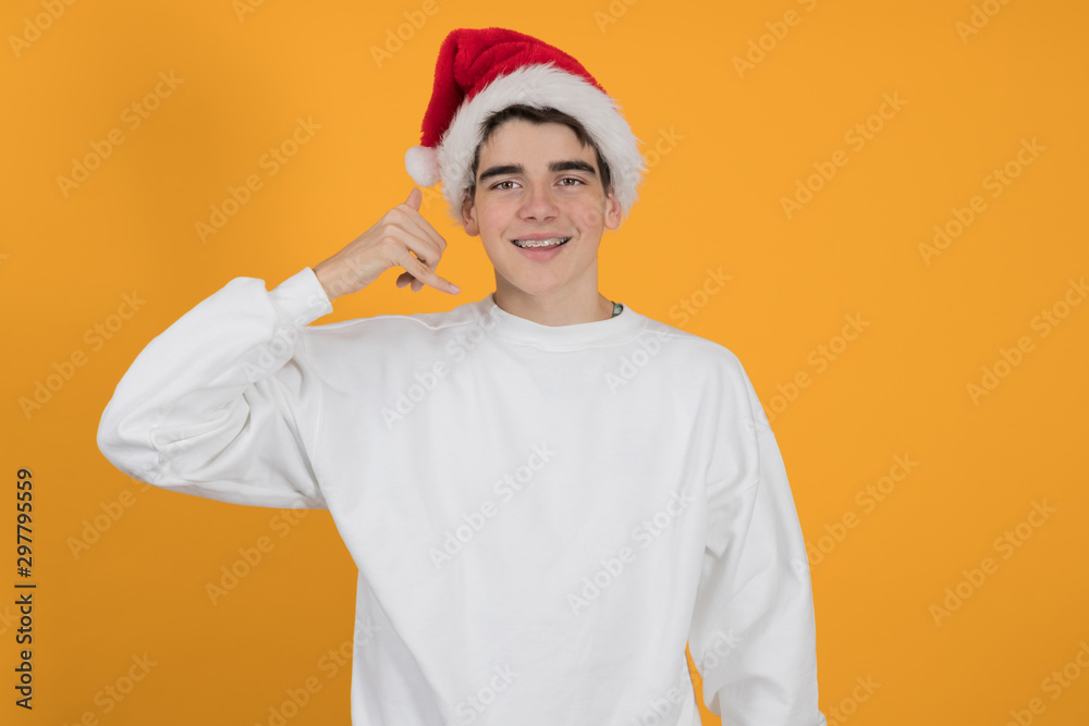 young teenage man with santa claus hat isolated on color background young teenage man with santa claus hat isolated on color background