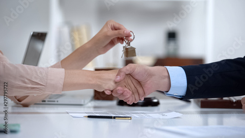 Woman shaking hands with lawyer holding house keys, successful purchase, deal photo