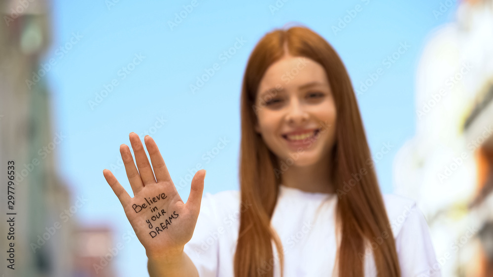 Believe in your dreams phrase written on teenager girl palm, motivation concept