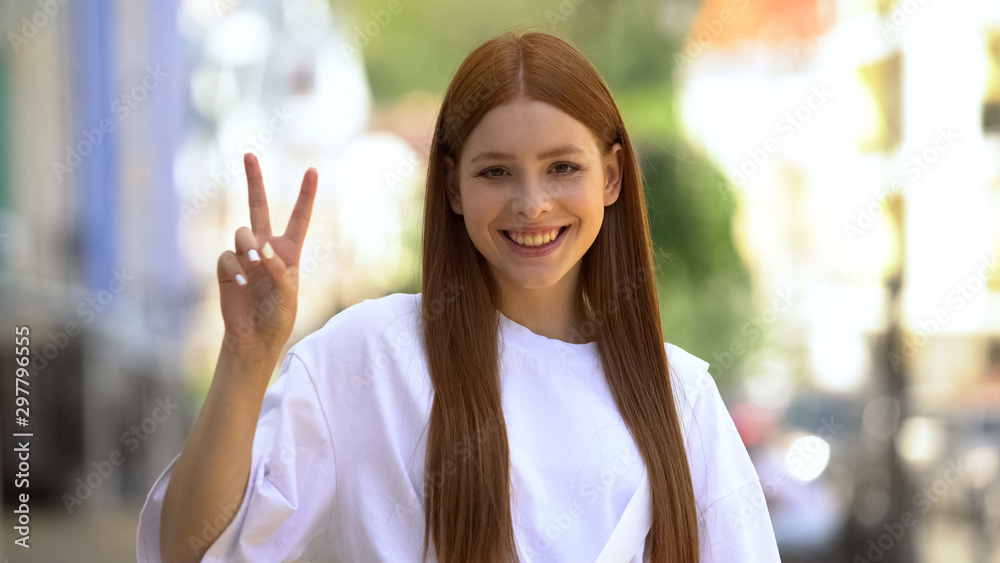 Beautiful teenager female showing victory sign gesture with fingers, success