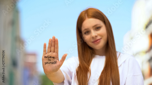 Young female showing palm with believe in yourself phrase, self-confidence