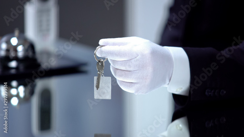 Fotografie Male hand in white glove giving key on chain, high quality service luxury hotel