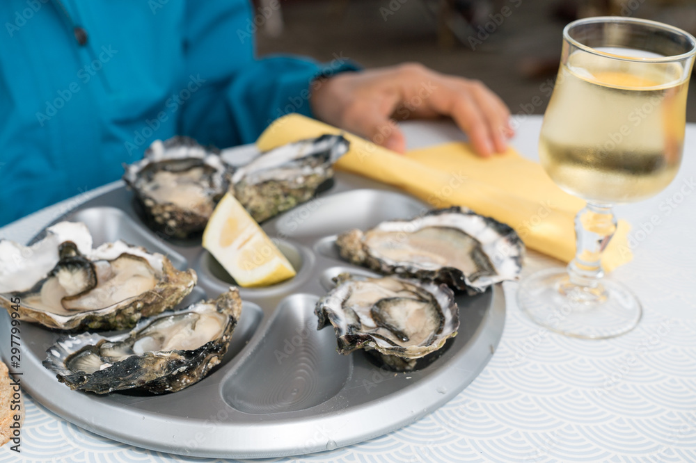 close up of delicious fresh oysters on the half shell with a glass of French white wine close up of delicious fresh oysters on the half shell with a glass of French white wine