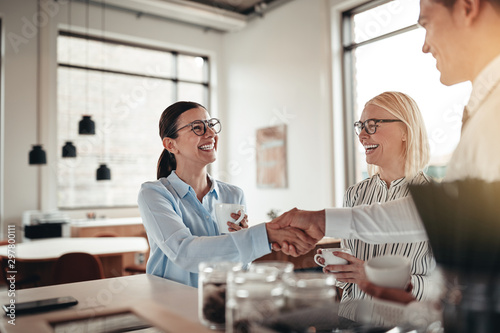 Smiling businesspeople shaking hands together during their coffe photo