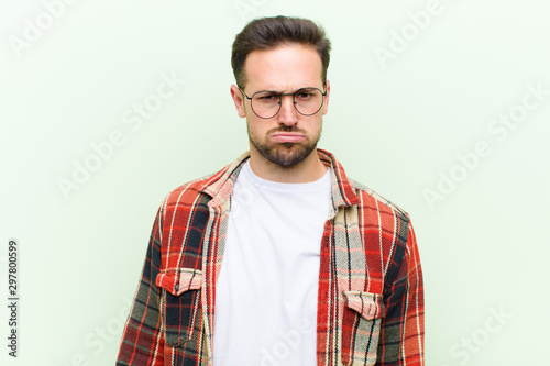 young handsome man feeling sad and whiney with an unhappy look, crying with a negative and frustrated attitude photo