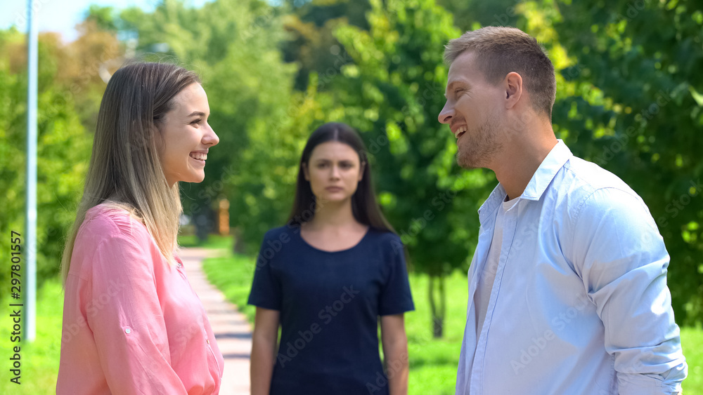 Smiling male and female looking each other, jealousy friend background, conflict Smiling male and female looking each other, jealousy friend background, conflict