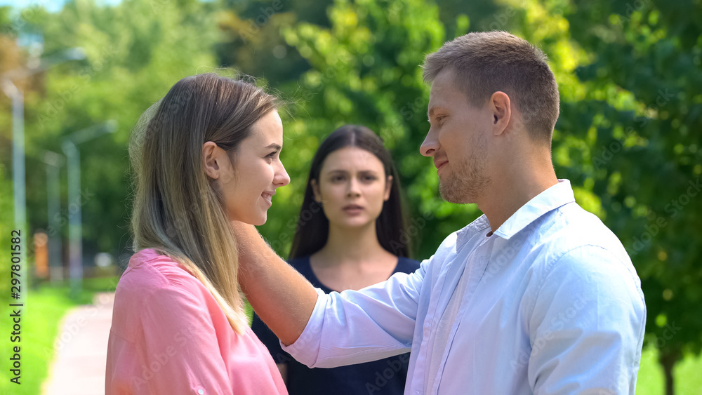 Girlfriend and boyfriend flirting outdoors, jealous woman background, betrayal Girlfriend and boyfriend flirting outdoors, jealous woman background, betrayal