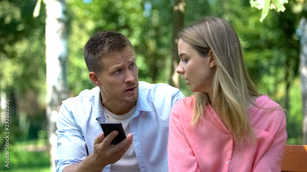 Jealous husband shouting at wife looking through messages on phone, breakup Jealous husband shouting at wife looking through messages on phone, breakup