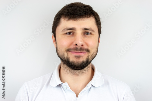 A smiling happy handsome bearded man with brown eyes in a white t-shirt